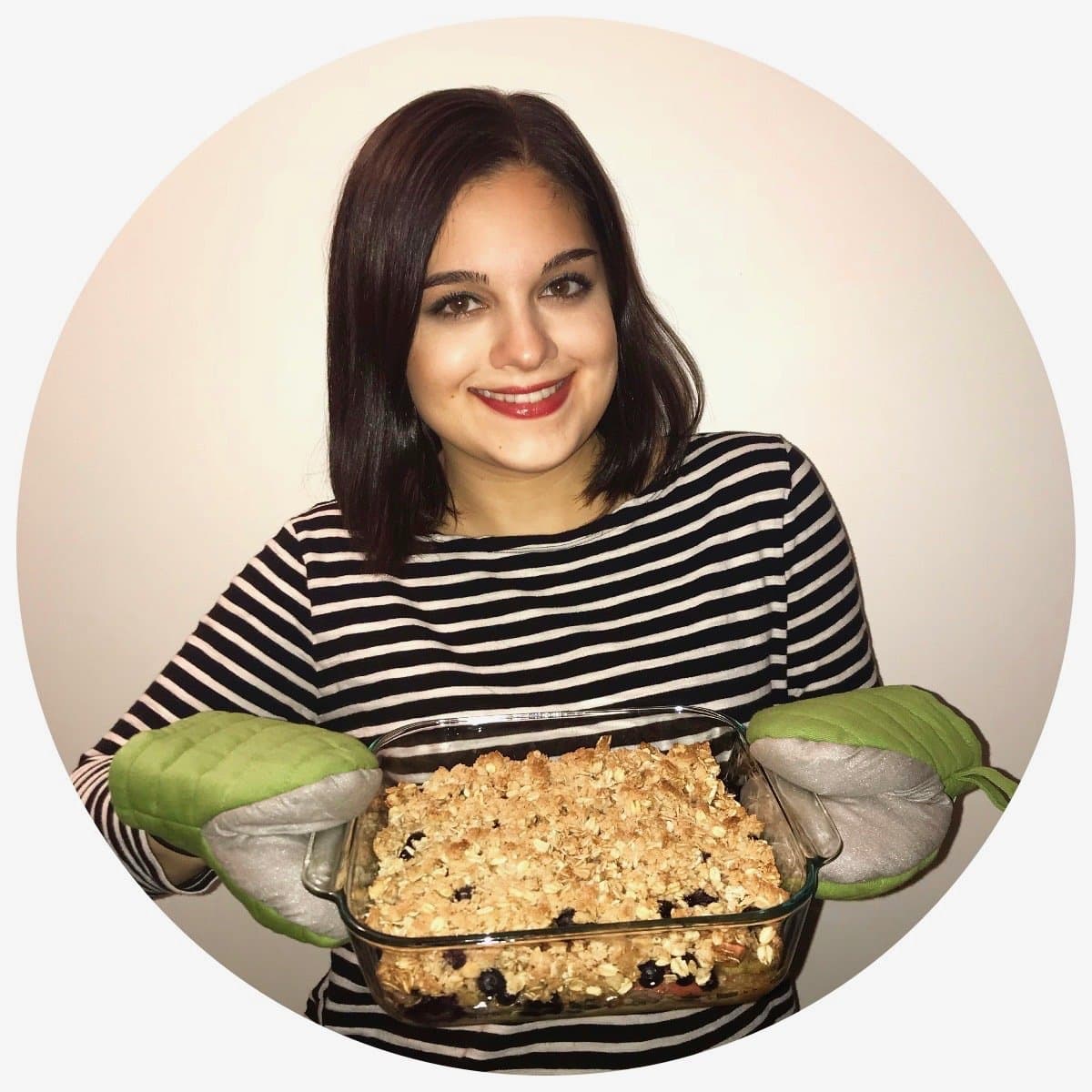 A woman holding a pan of apple blueberry crumble.