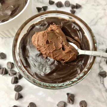 A small bowl of chocolate mousse, with a spoonful of it on top.
