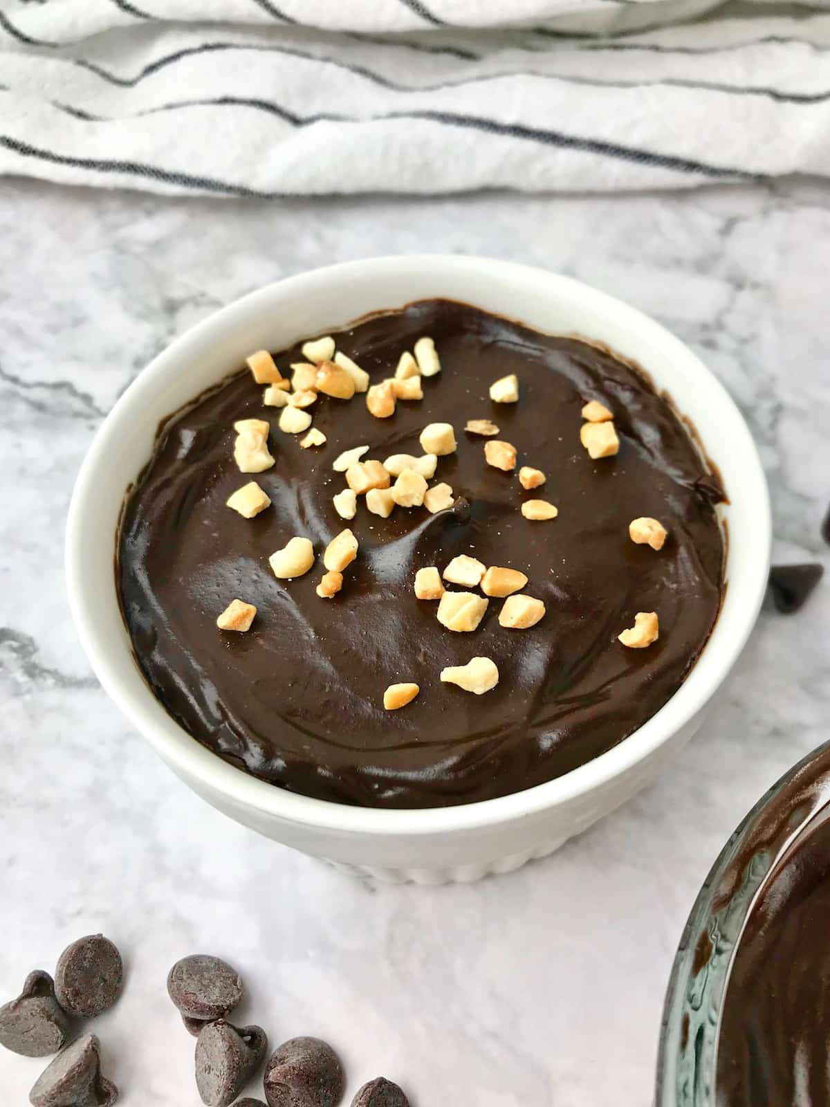 A bowl of chocolate mousse topped with chopped peanuts.