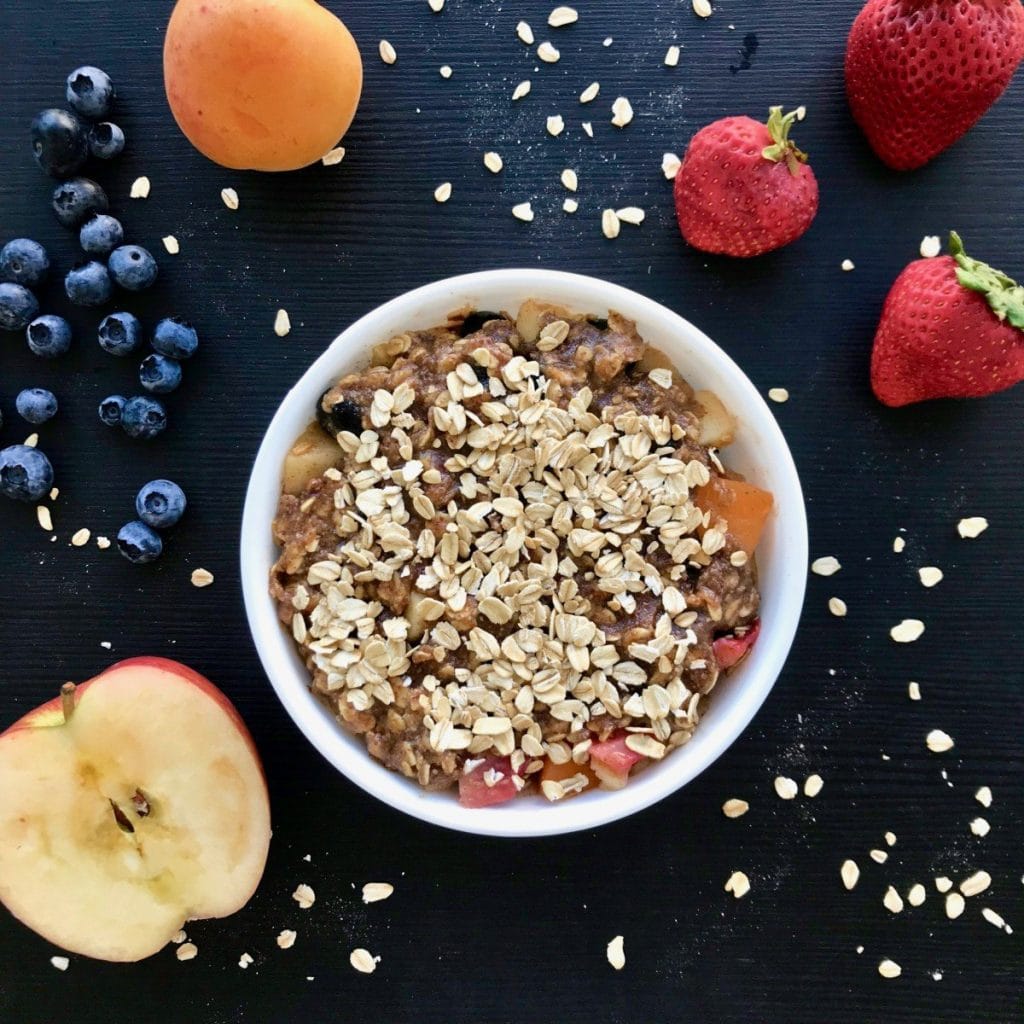 Vegan fruit dessert in a bowl surrounded by fruit.