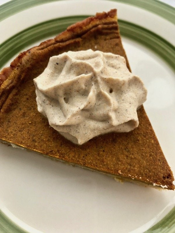 Pumpkin whipped cream on a slice of pumpkin pie.