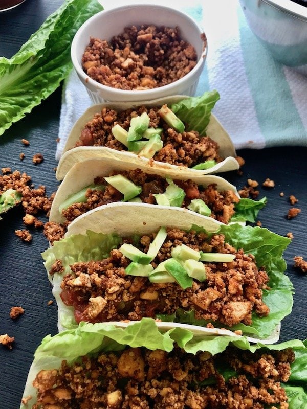 Vegan tacos filled with tofu crumble, lettuce, salsa, and avocado.