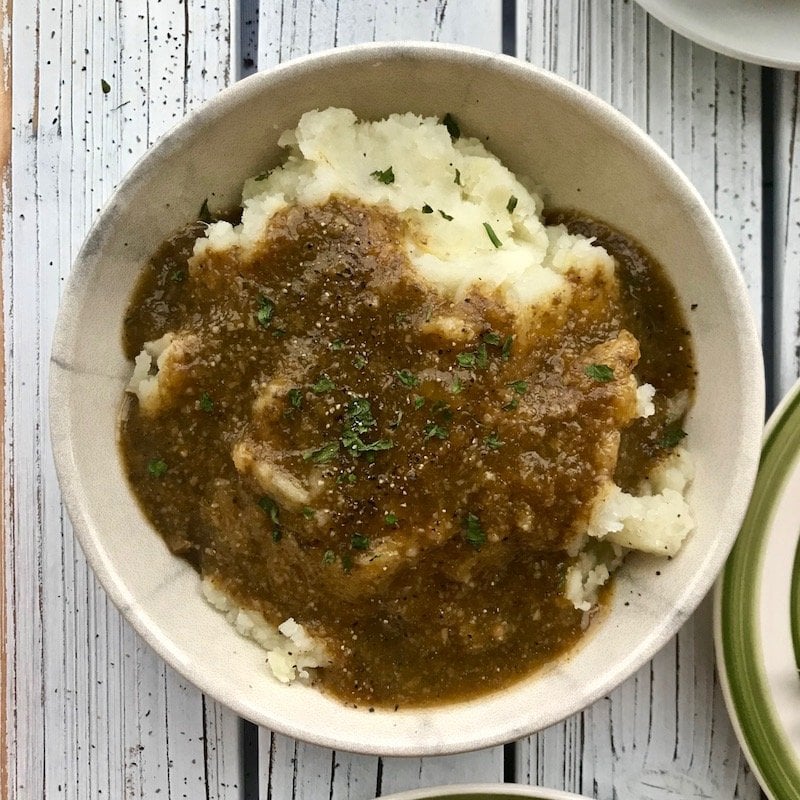 Bowl of mashed potatoes with plant-based mushroom gravy on top.