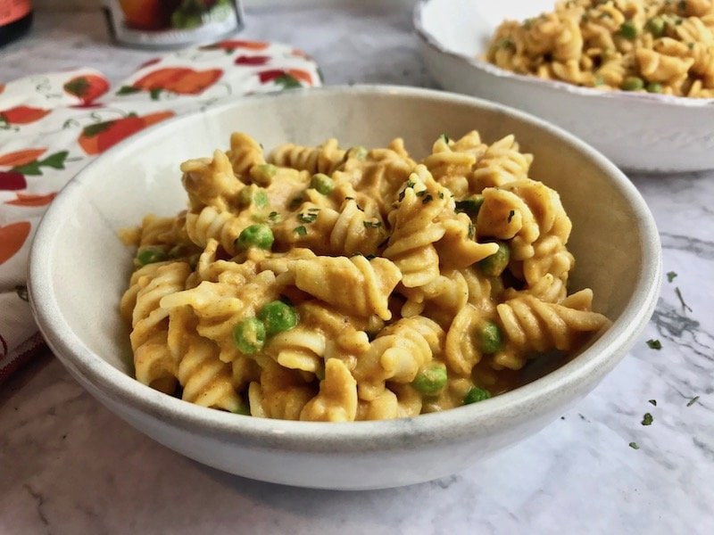 Close-up of bowl of vegan pumpkin pasta with peas.