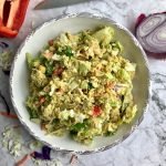 Vegan chickpea salad in a large bowl with ingredients in the background.