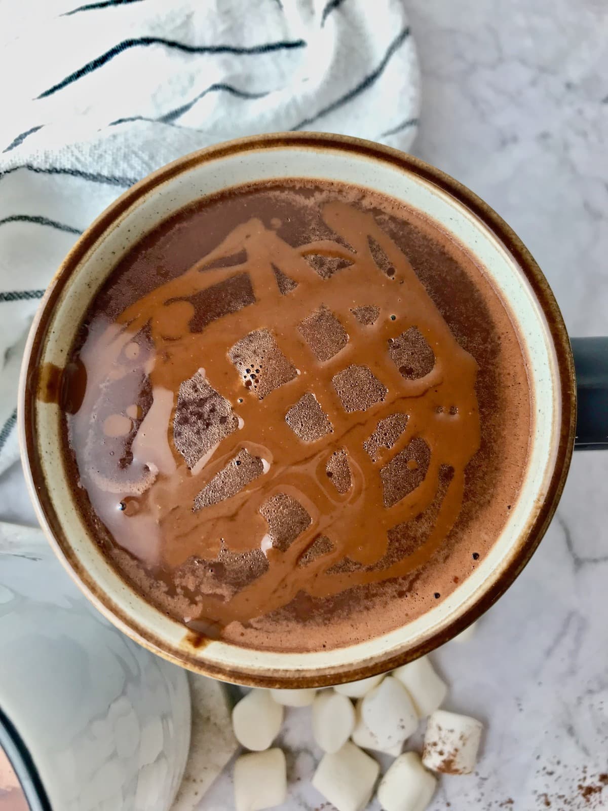 A mug of hot chocolate topped with chocolate sauce.