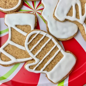 Christmas-shaped cookies with white frosting on a Christmas plate.