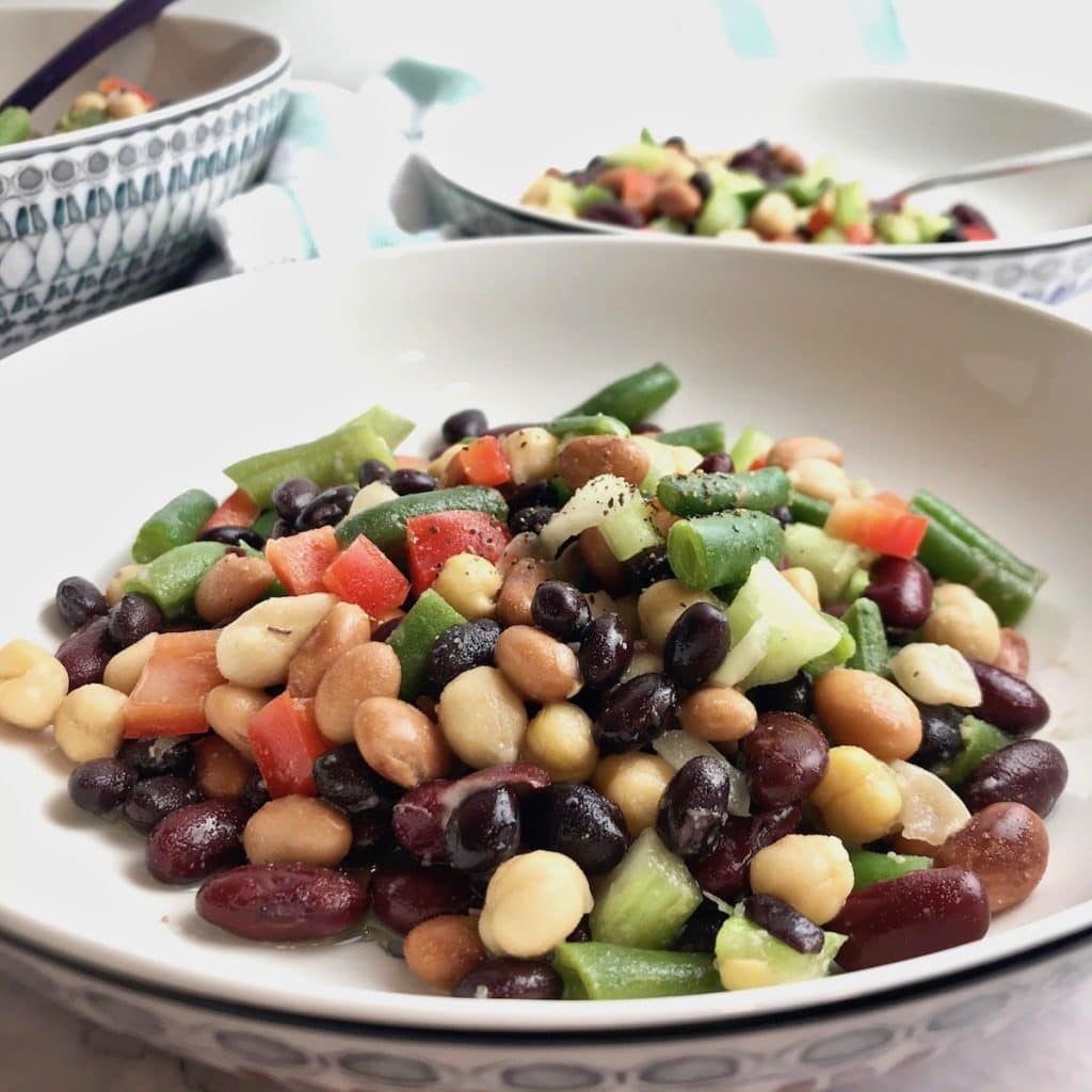 Close up of 5 bean salad in a bowl, with more in the distant background.