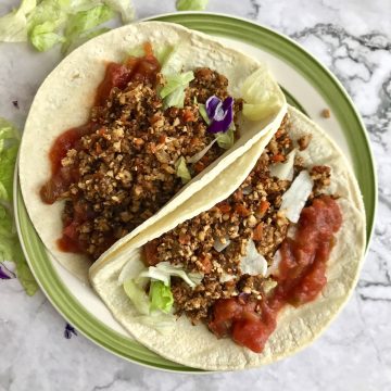 Cauliflower taco meat in soft corn tortillas with salsa and lettuce.