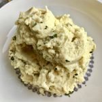 A bowl of mashed cauliflower topped with parsley.