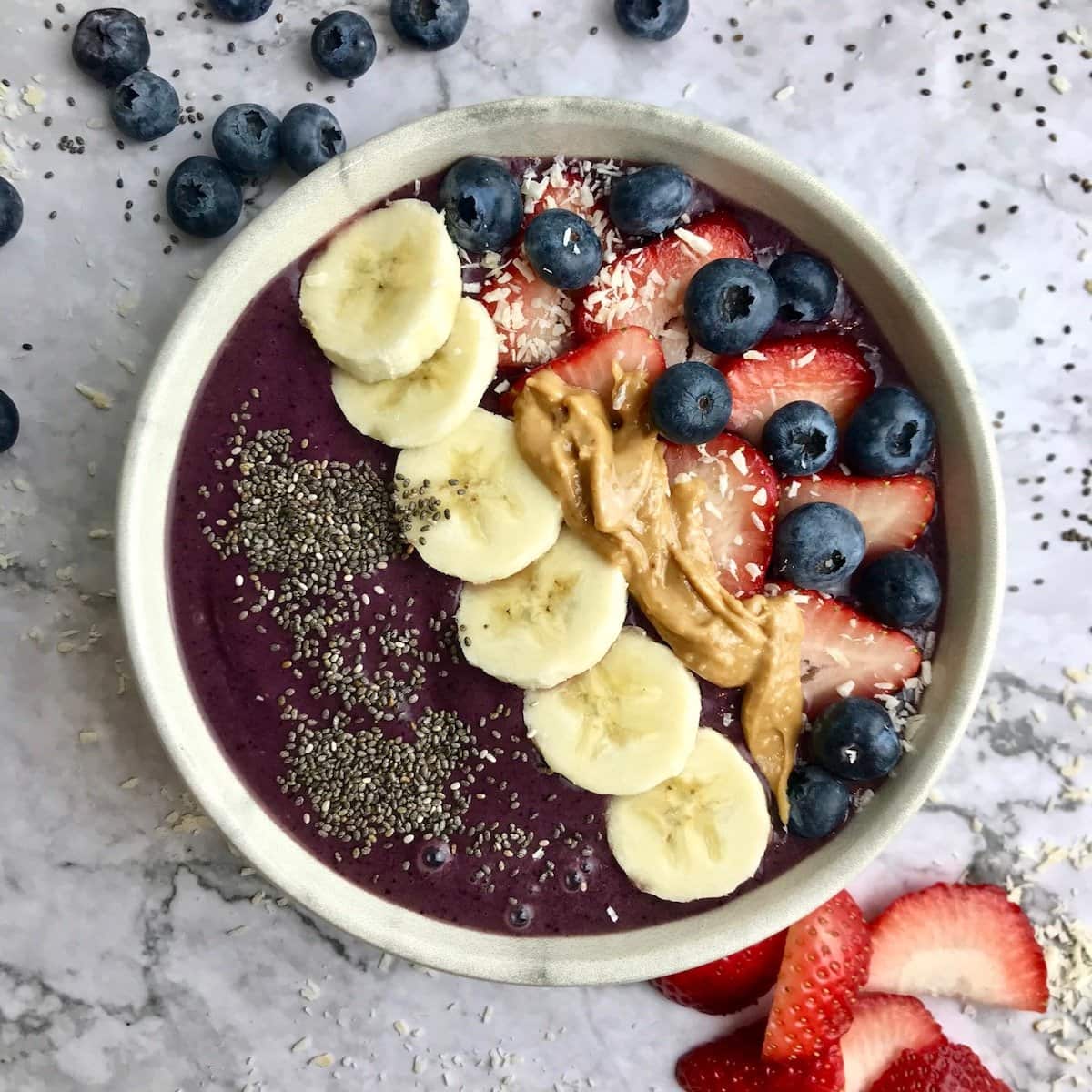 Peanut butter acai bowl topped with fruit, chia seeds, coconut flakes, and peanut butter.