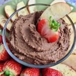 Chocolate peanut butter hummus with an apple slice and strawberry slice dipped in it.