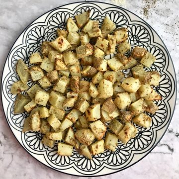 Oil free roasted potatoes on a plate with a black and white pattern.