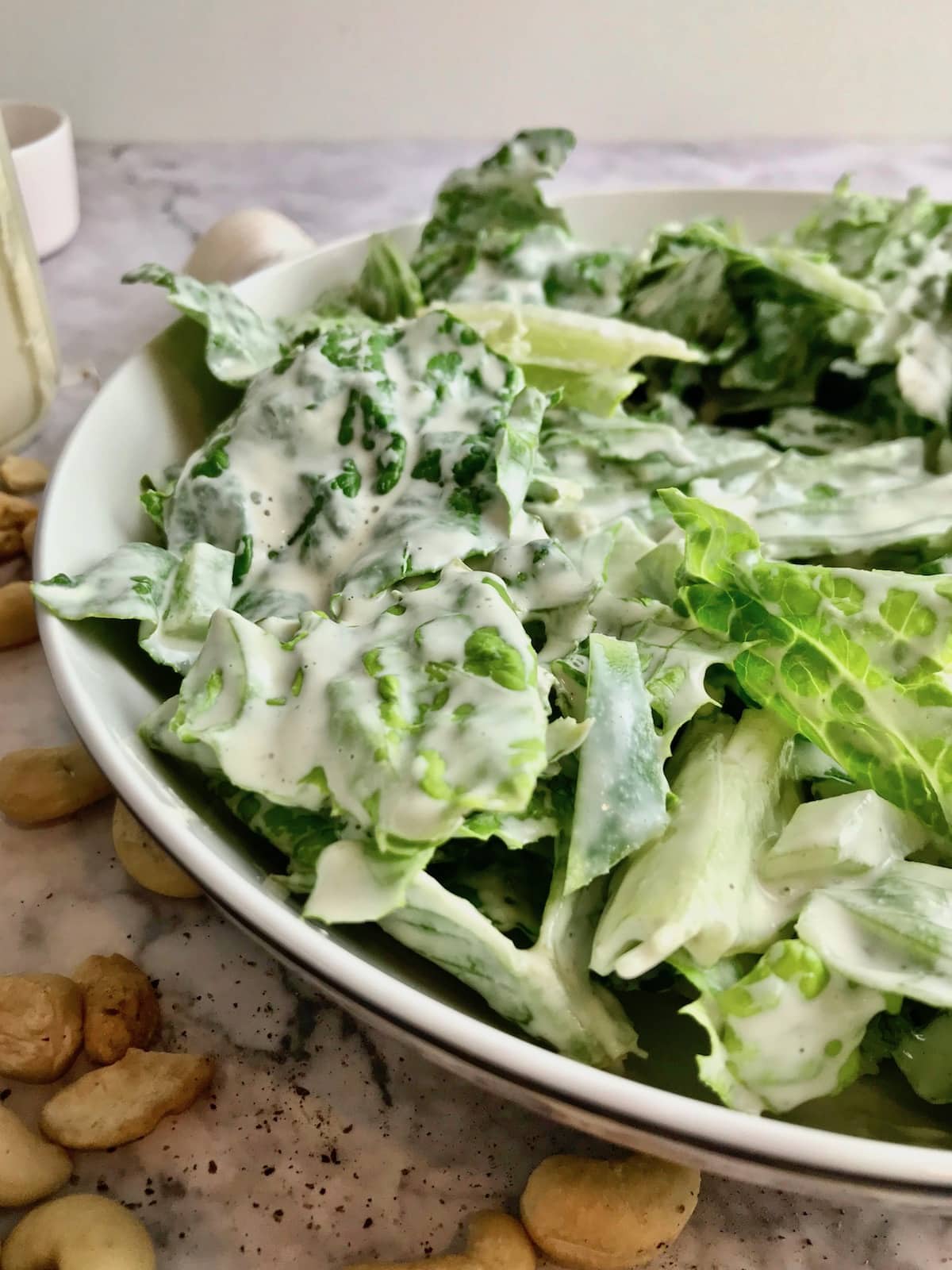 A bowl of romaine lettuce covered in white dressing. 