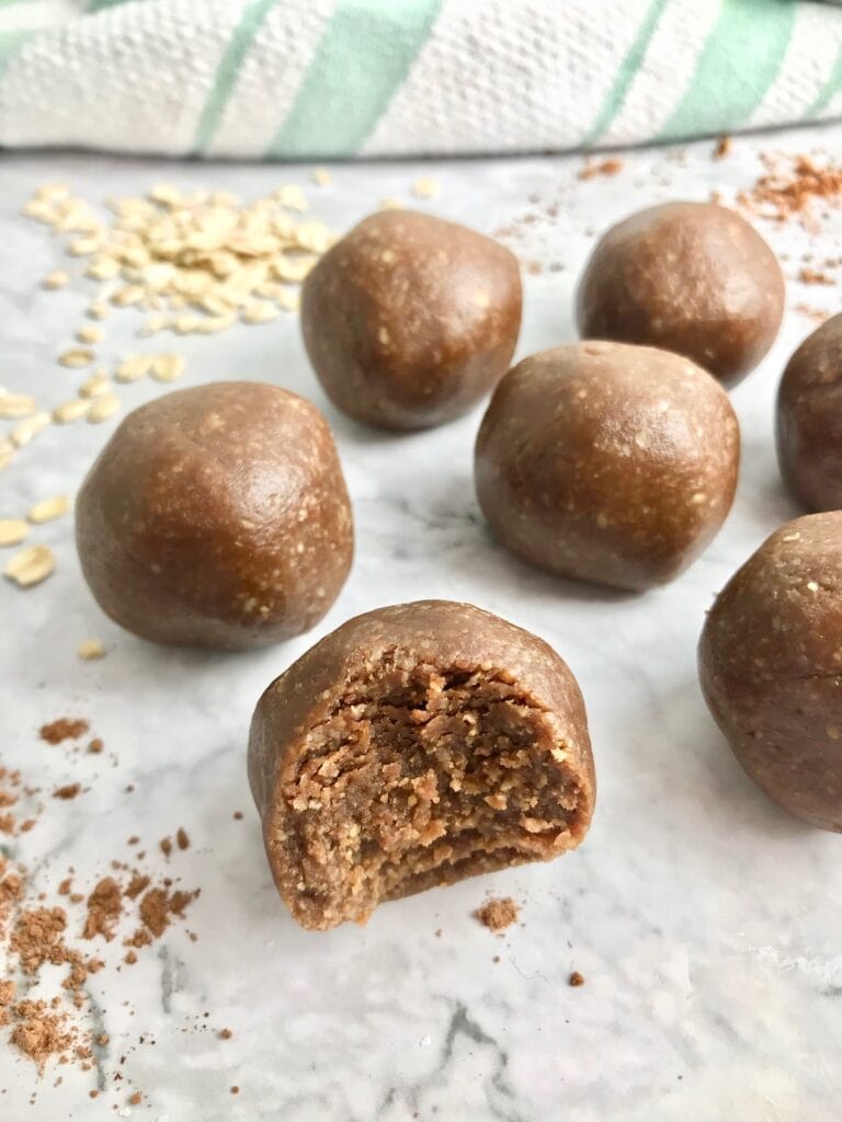 Cookie dough ball with a bite taken out of it, with more cookie dough balls in the background. 