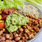 Text that says burrito bowl, over a bowl full of rice, beans, and vegetables.