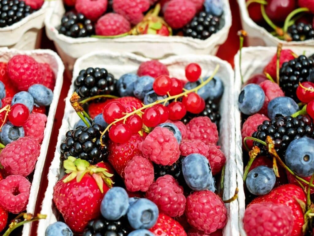 Containers of berries, including raspberries, blueberries, strawberries, and blackberries.