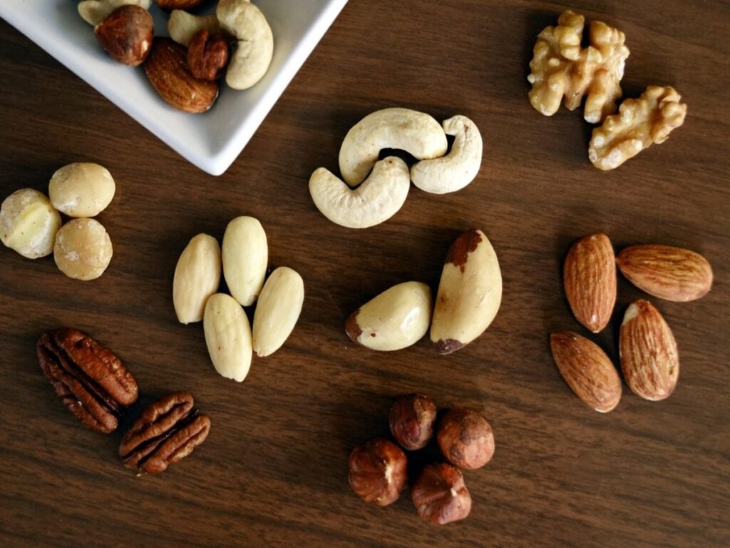 Nuts laid out on a table, including almonds, walnuts, cashews, hazelnuts, and pecans.