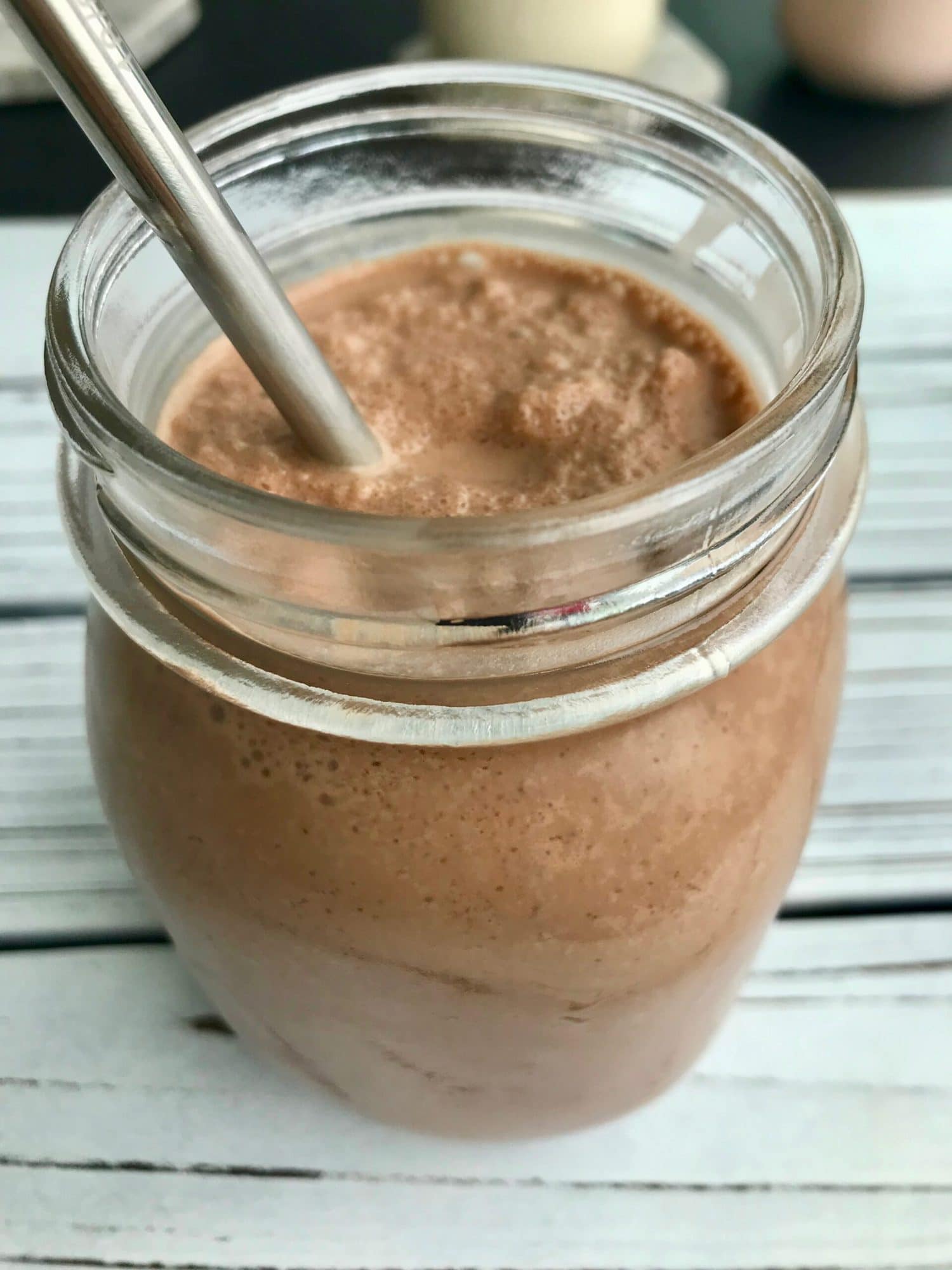 Chocolate coconut milkshake in a glass jar with a metal straw.