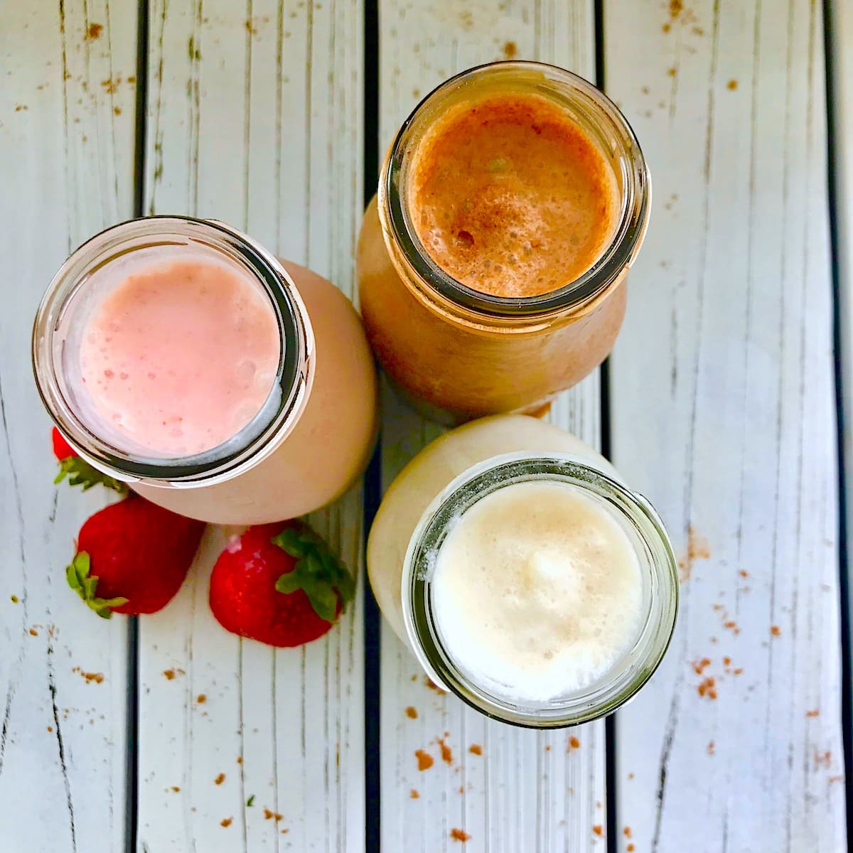 Overhead view of three milkshakes including one chocolate, one vanilla, and one strawberry.