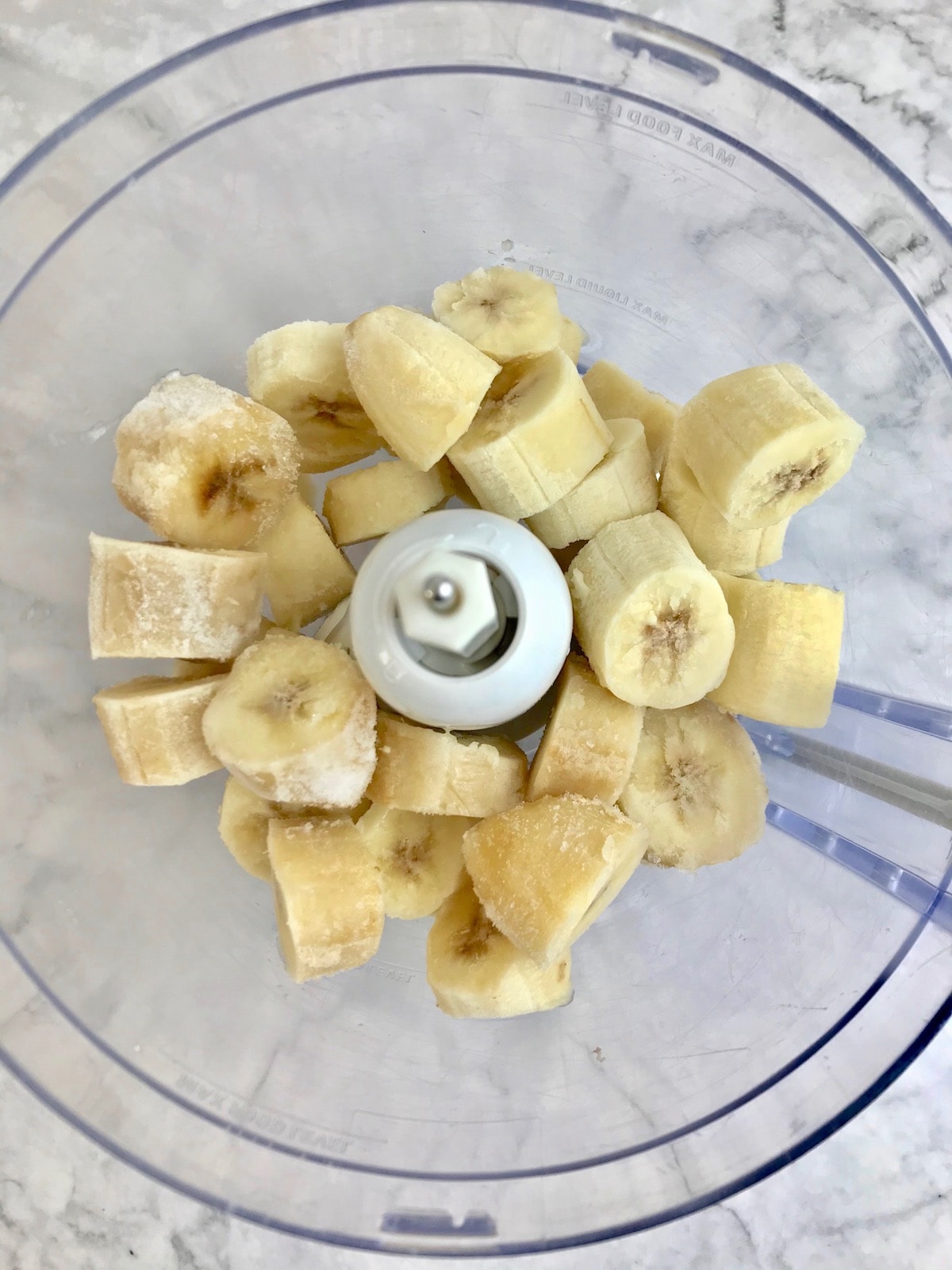 Frozen banana pieces in a food processor.