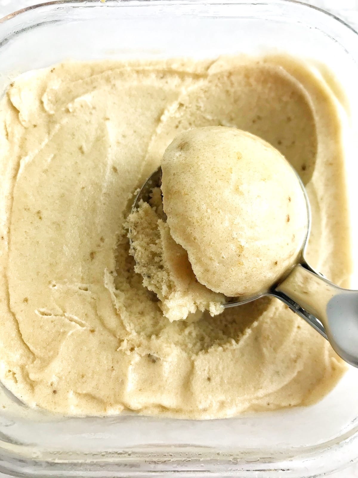 A scoop being taken from a contain of frozen banana nice cream.