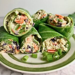 Collard green wraps on a plate, filled with quinoa and vegetables.