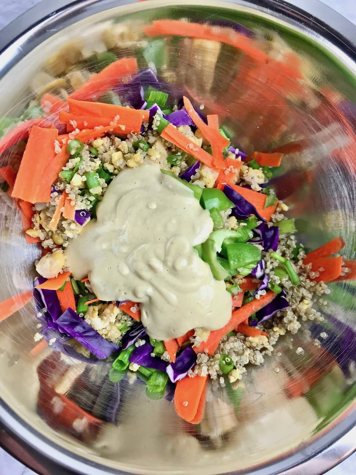 Quinoa, chickpeas, and vegetables in a bowl topped with a maple Dijon dressing.