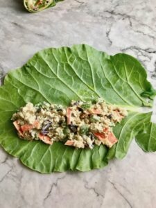 A collard leaf with quinoa and vegetables laid on top of it.