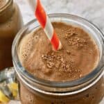 A chocolate smoothie with an orange and white striped straw.