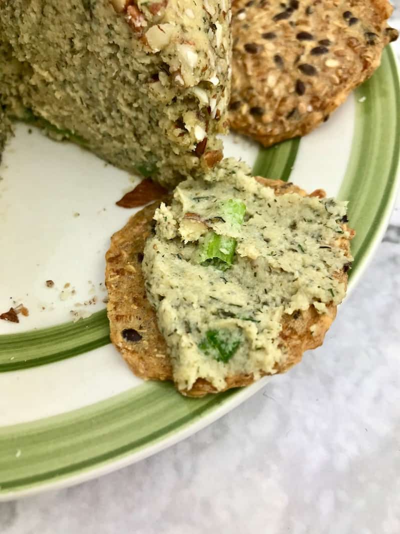 A cracker with cheese ball spread on it.