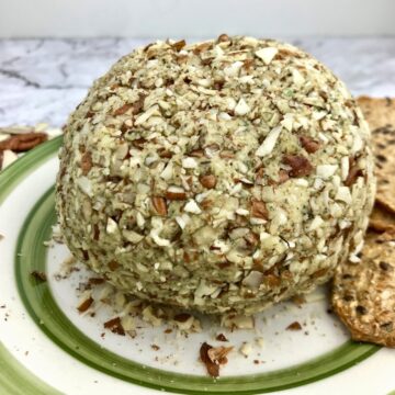 A cheese ball covered in nuts on a plate.