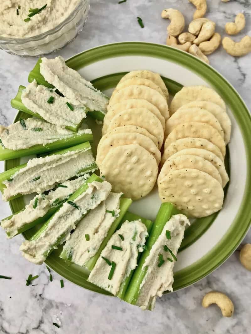 A plate of crackers and celery sticks with cream cheese spread on them.