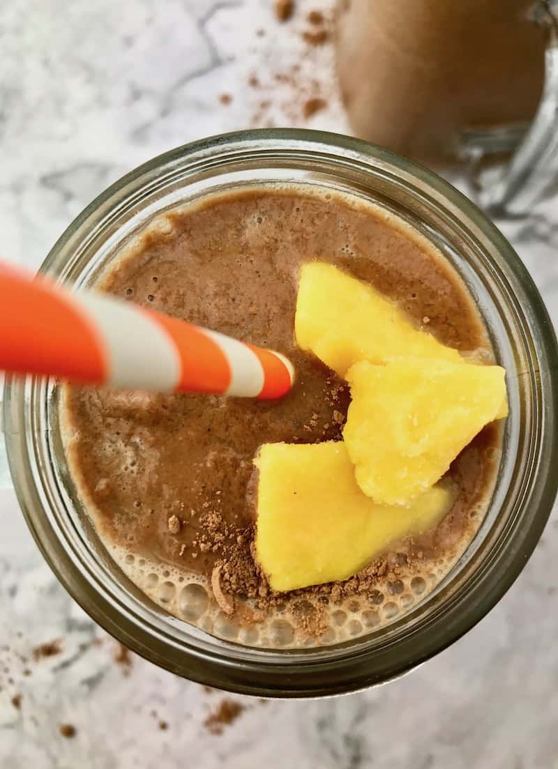 A chocolate mango smoothie with three pieces of mango on top.