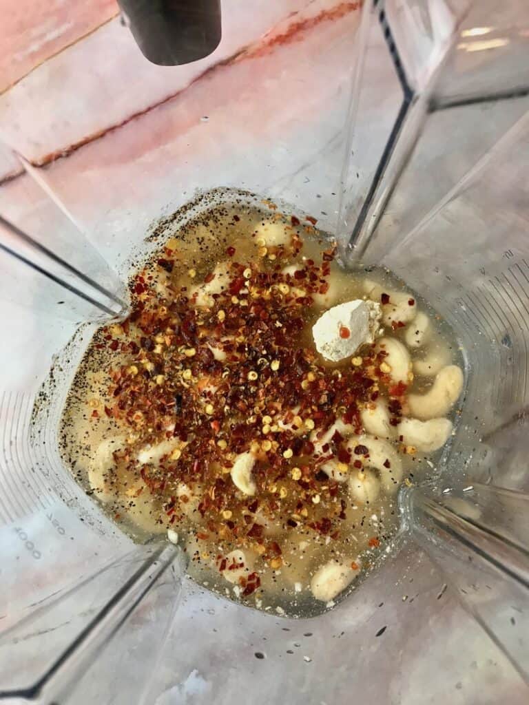 Cashews, spices, water, and red pepper flakes in a blender.