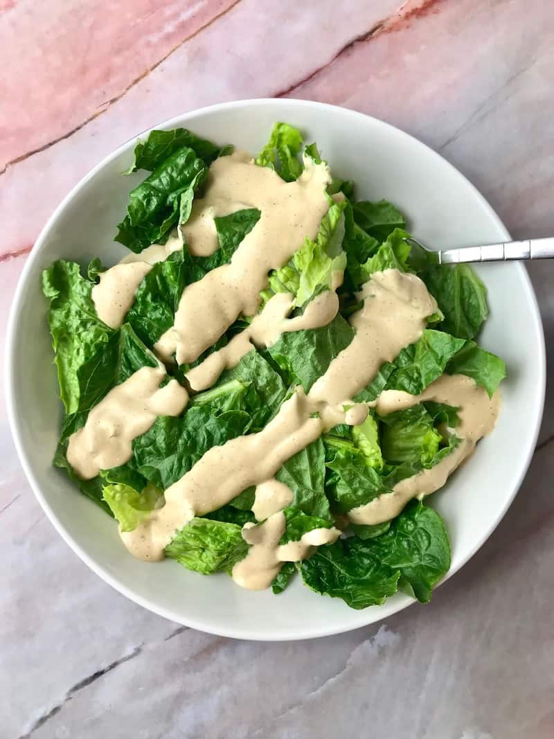 Cashew dressing drizzled on a bowl of lettuce.