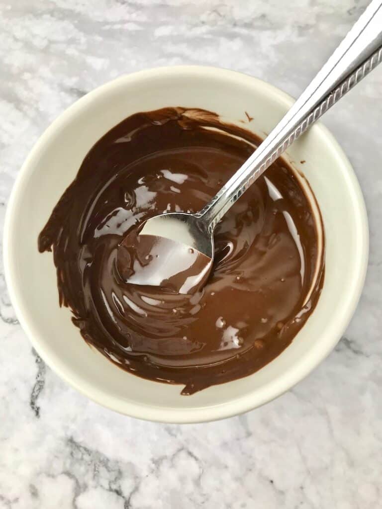 Melted chocolate in a small bowl with a spoon.