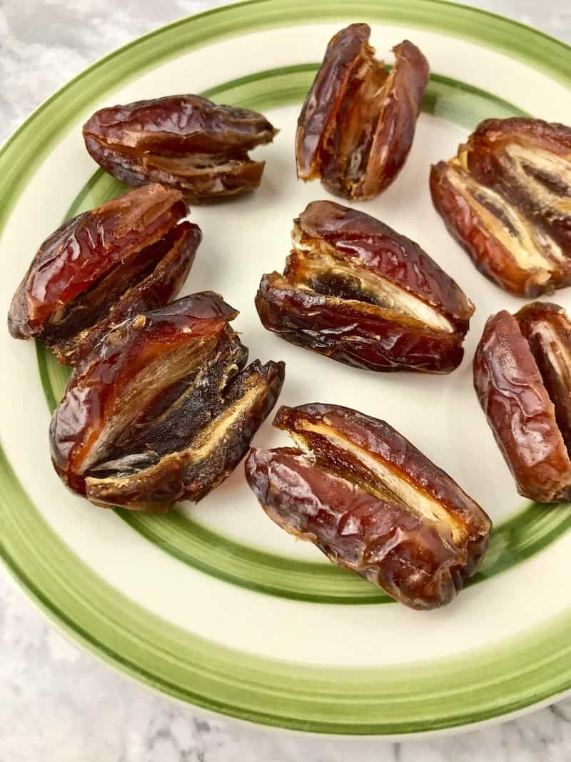 A plate of Medjool dates that are open lengthwise.