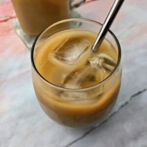 A cup of iced coffee with a metal straw in it.