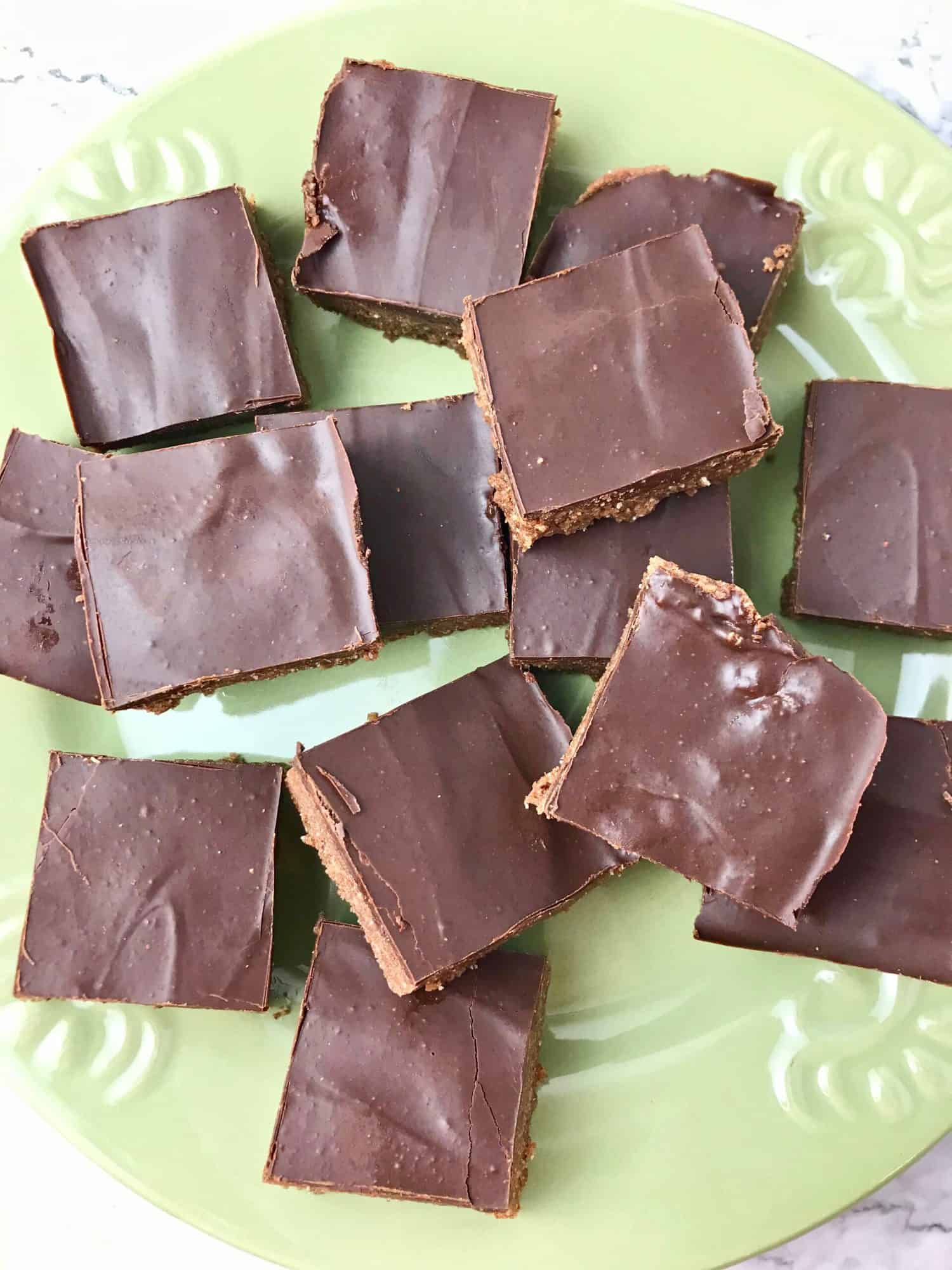 Chocolate almond butter squares on a green plate.