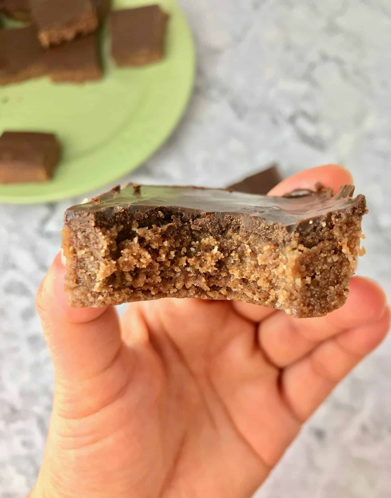 A hand holding a chocolate almond butter bar.