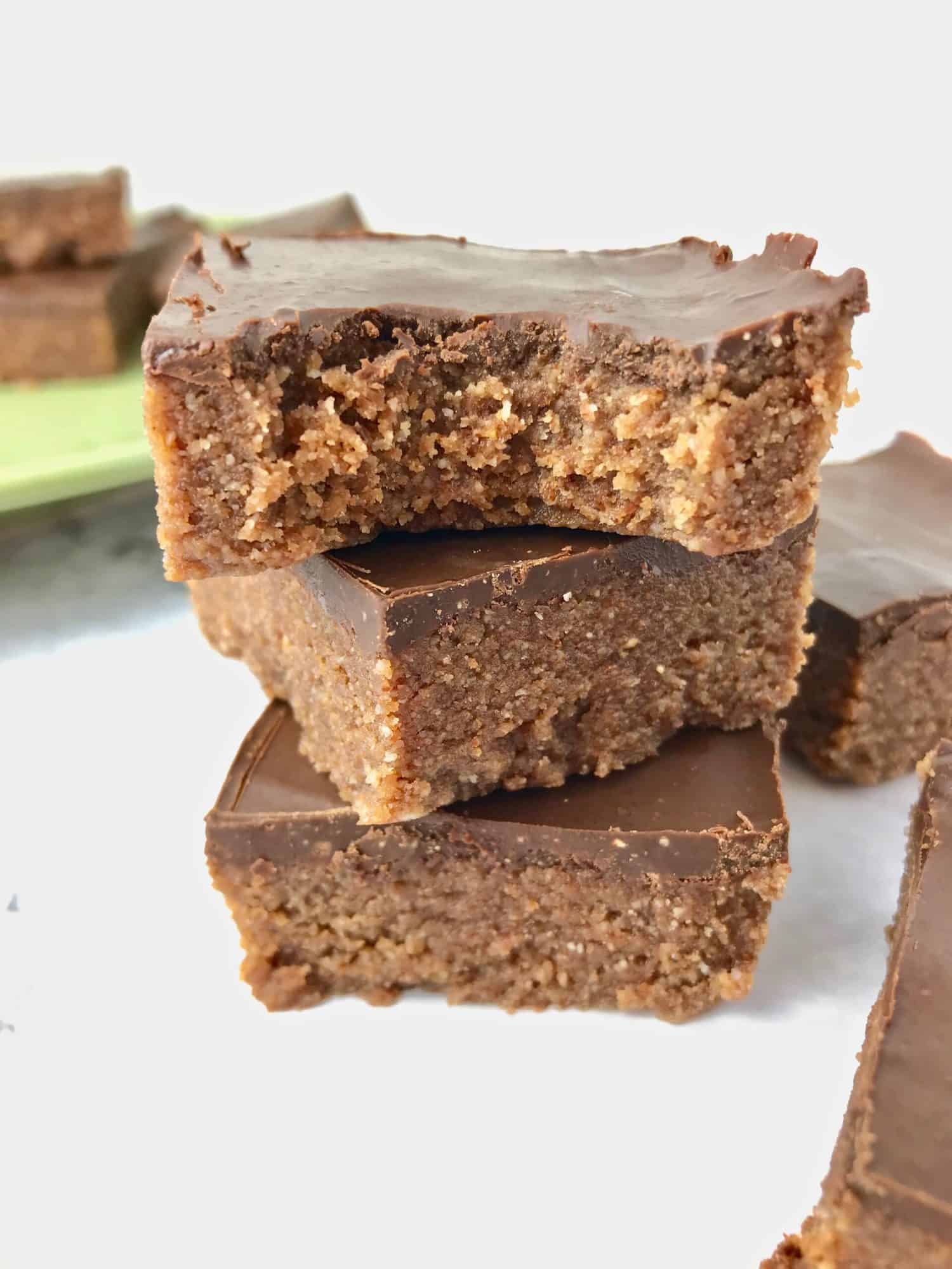 Three stacked almond butter bars, with the top one missing a bite from it.