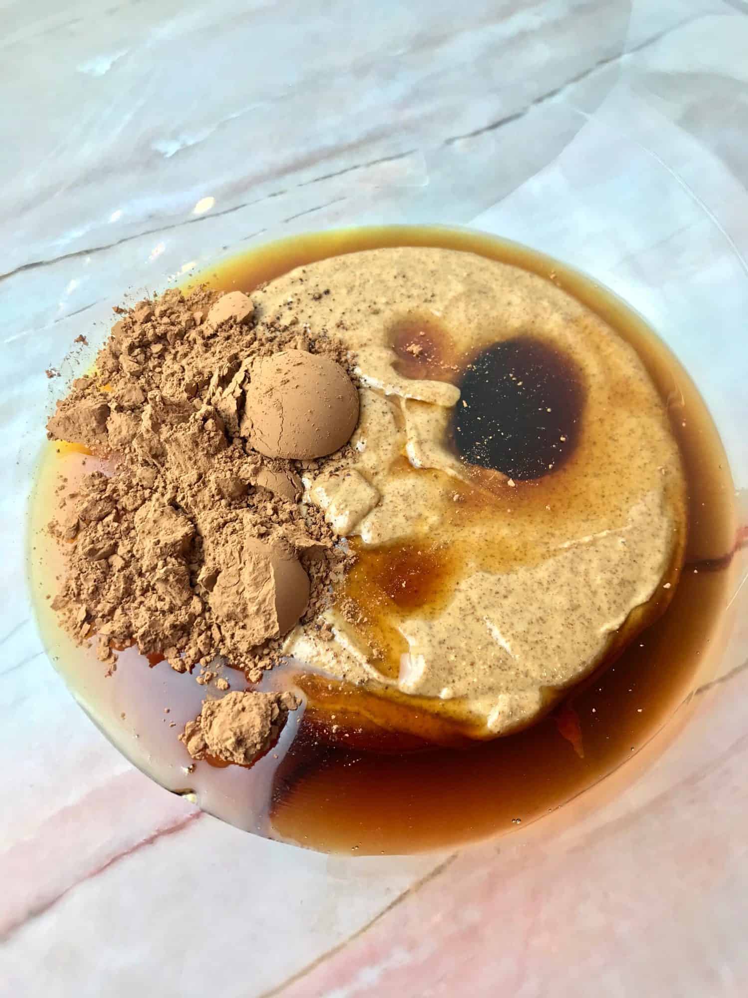 A mixing bowl with almond butter, maple syrup, and cacao powder.