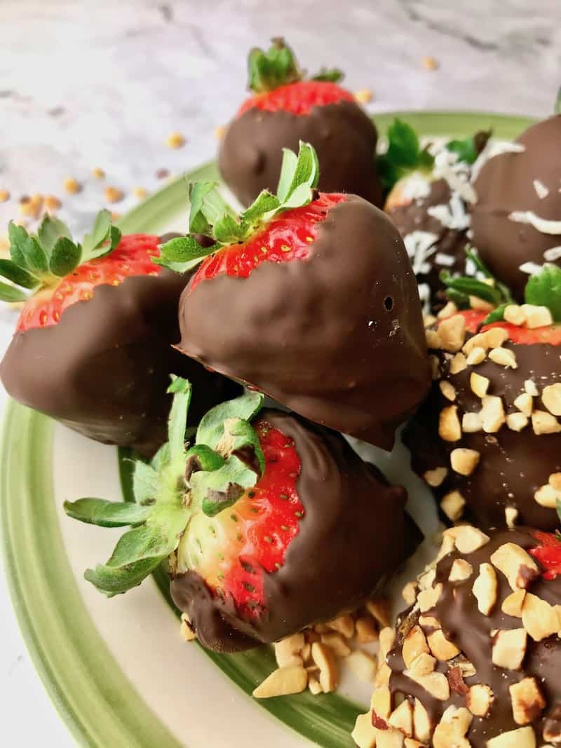 Chocolate dipped strawberries, some of which are topped with chopped peanuts.