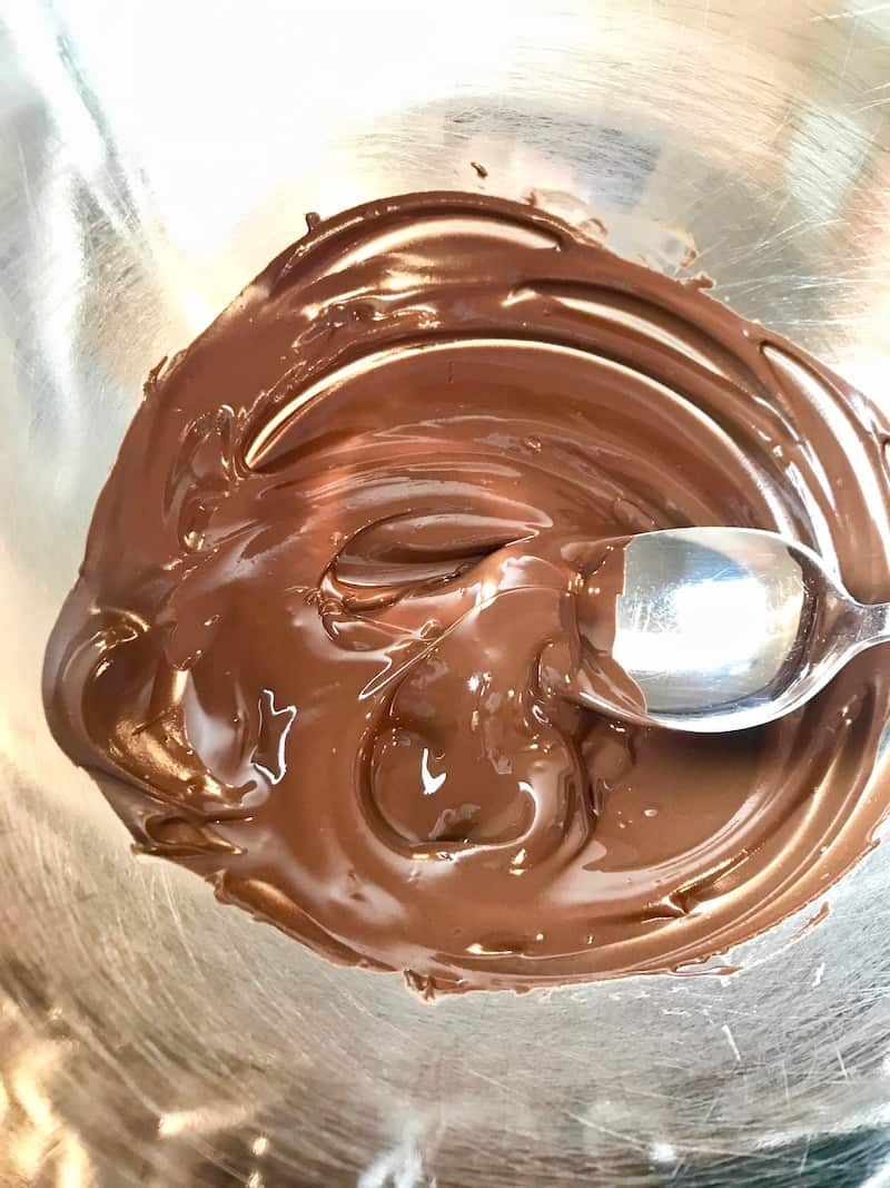 Melted chocolate with a spoon in a bowl.