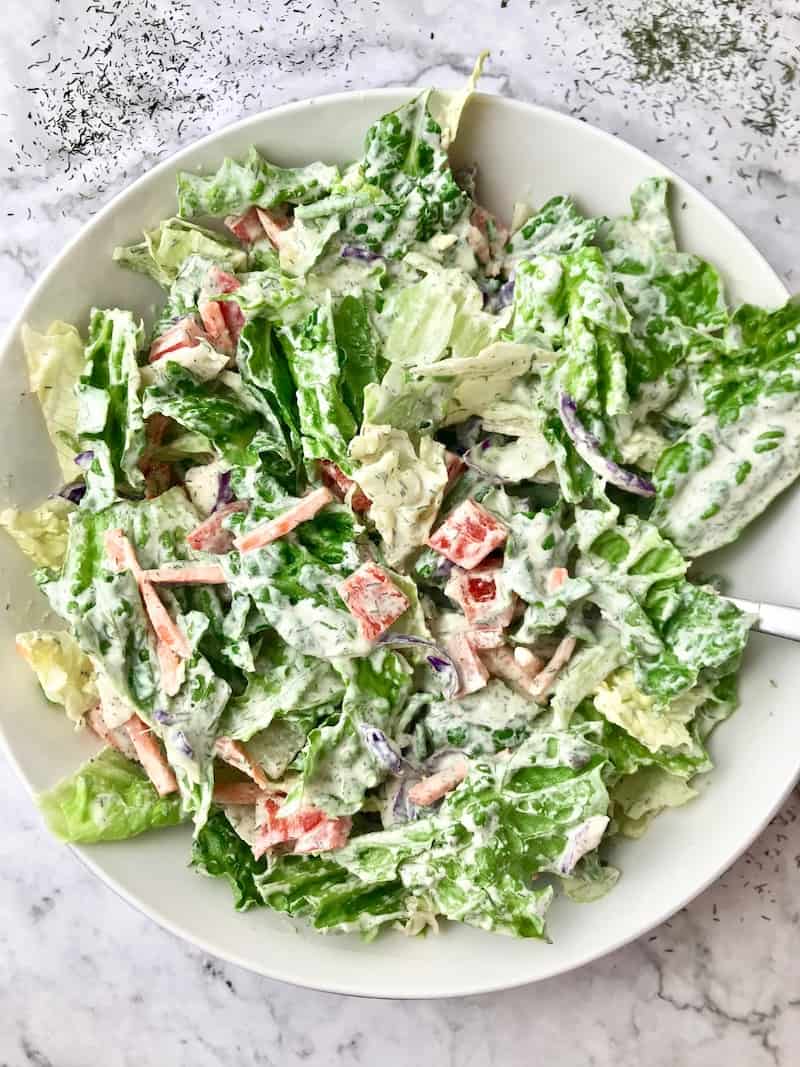 A salad covered in a white dill dressing.