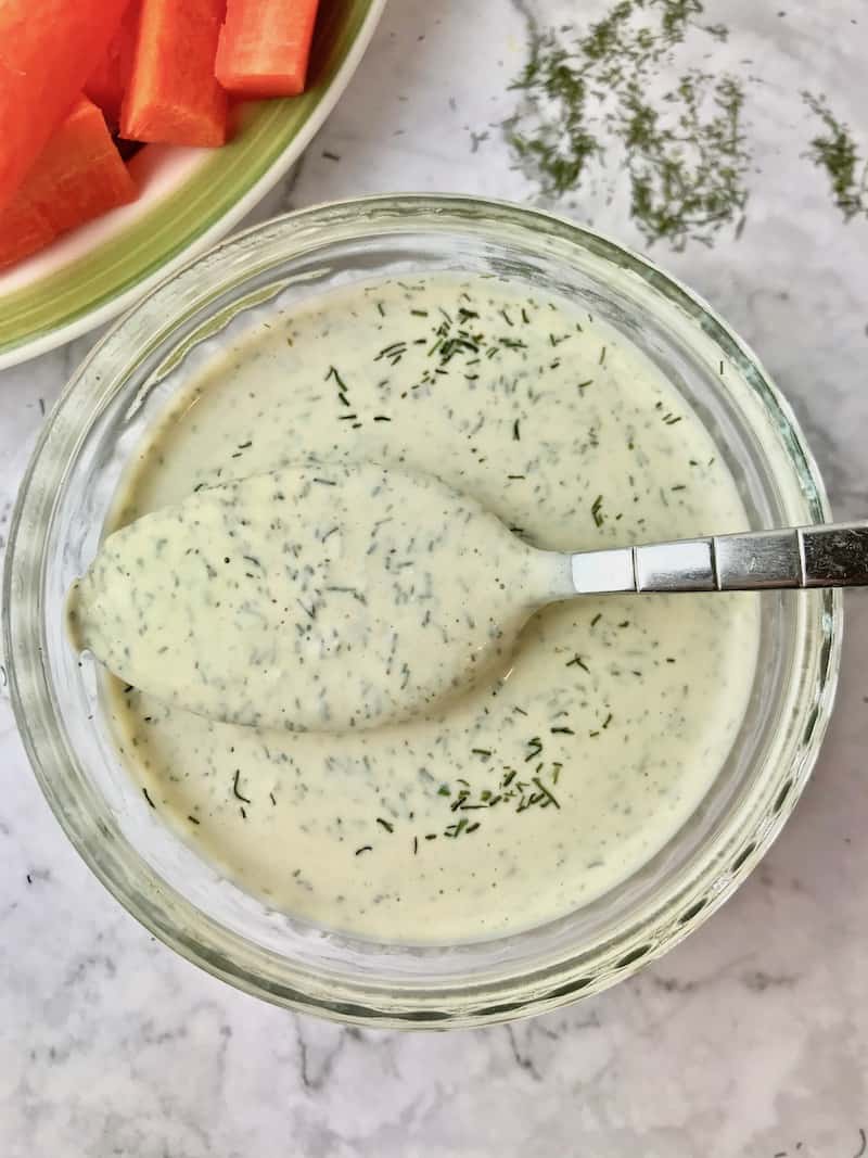 A bowl of dressing with a spoonful over it.