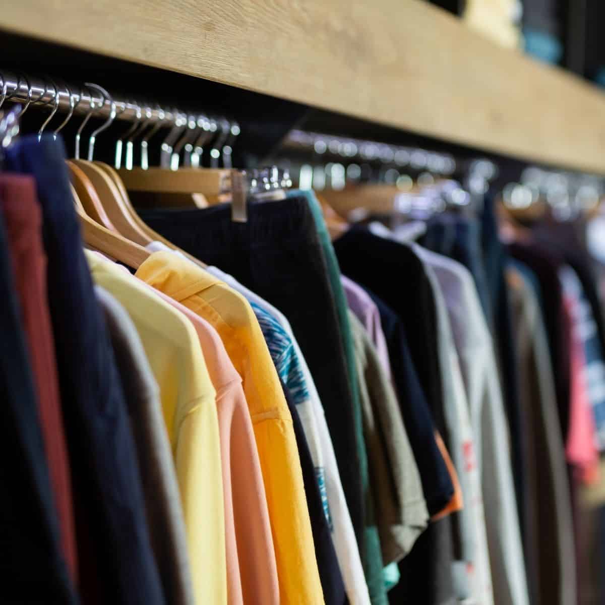 Clothing of various colors hanging on a rack.