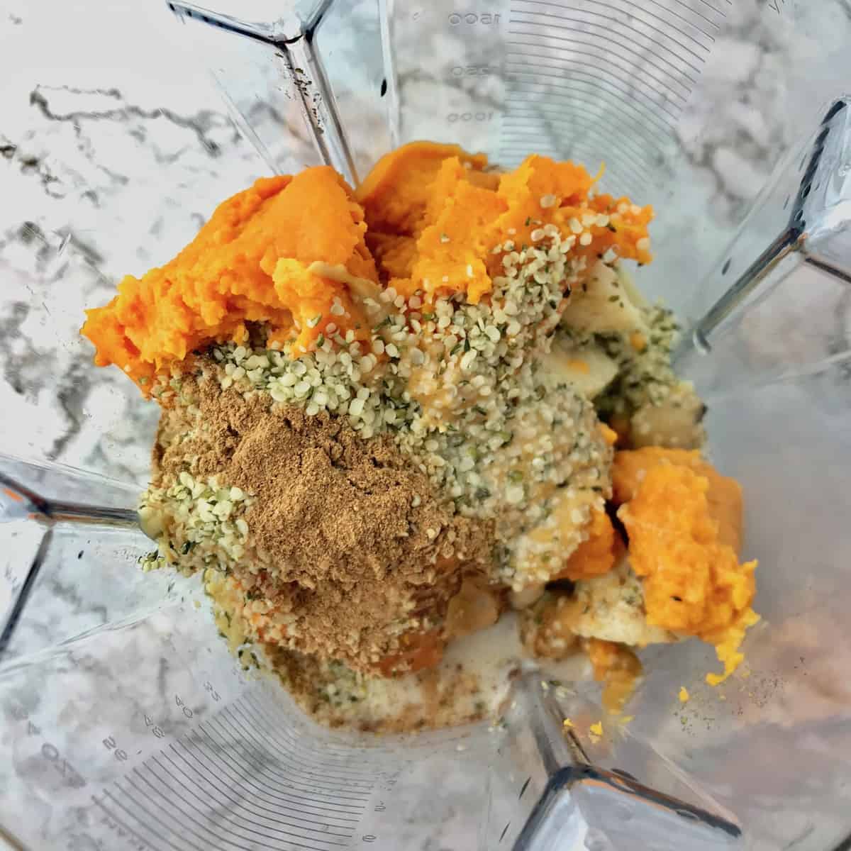 Mashed sweet potato, frozen banana, hemp hearts, and pumpkin pie spice in a blender.