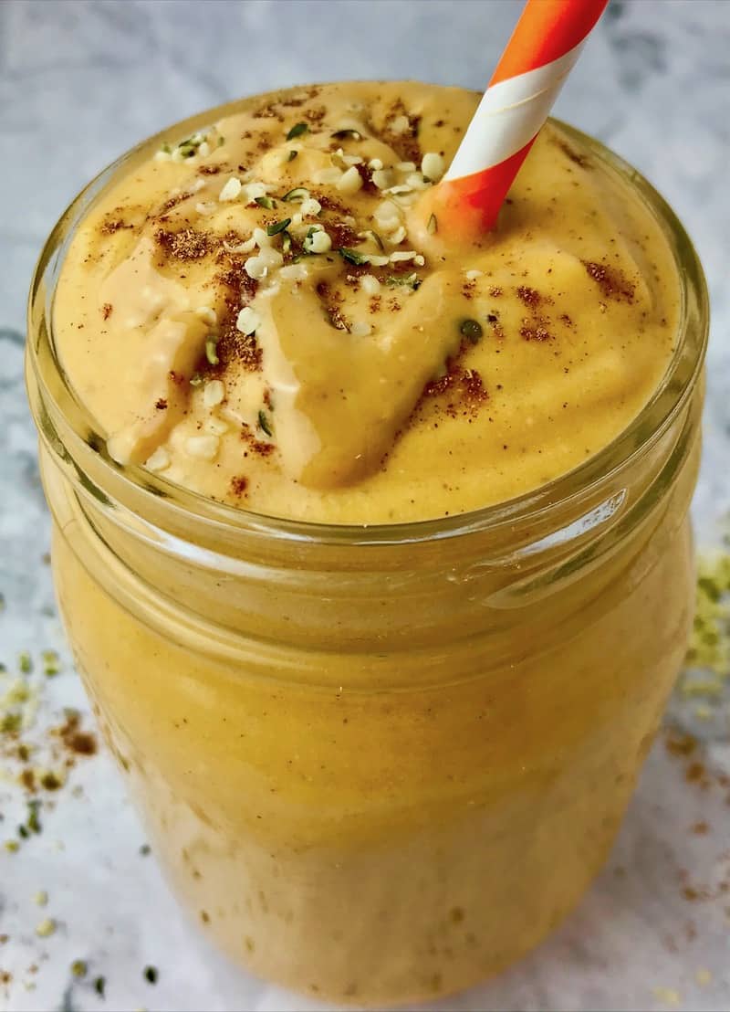 An orange smoothie with peanut butter and hemp hearts on top.